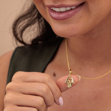 Woman Holding Gold Fatima Hand Charm Necklace | Hamsa Pendant Necklace