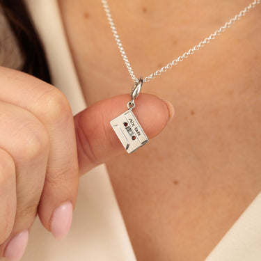 Close Up silver cassette tape necklace in hand for scale