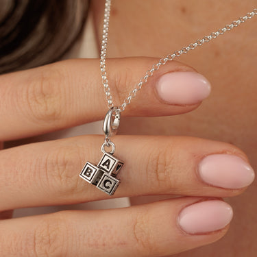 Woman Holding a Silver ABC Building Block Pendant Necklace | Baby Block Charm Necklace Close Up