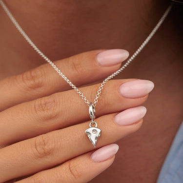 Silver necklace with cheese slice charm held by hand 