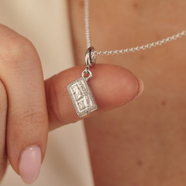 Woman Holding Silver Malted Milk Biscuit Charm Necklace with Cow and Gate Design